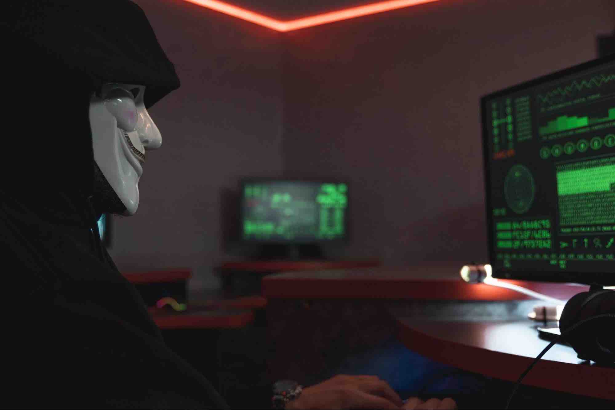 Un hacker avec un masque anonymous derrière son ordinateur.